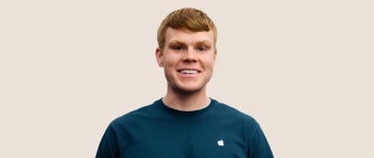 Portrait of a smiling Apple Retail team member with short, dark blond hair.