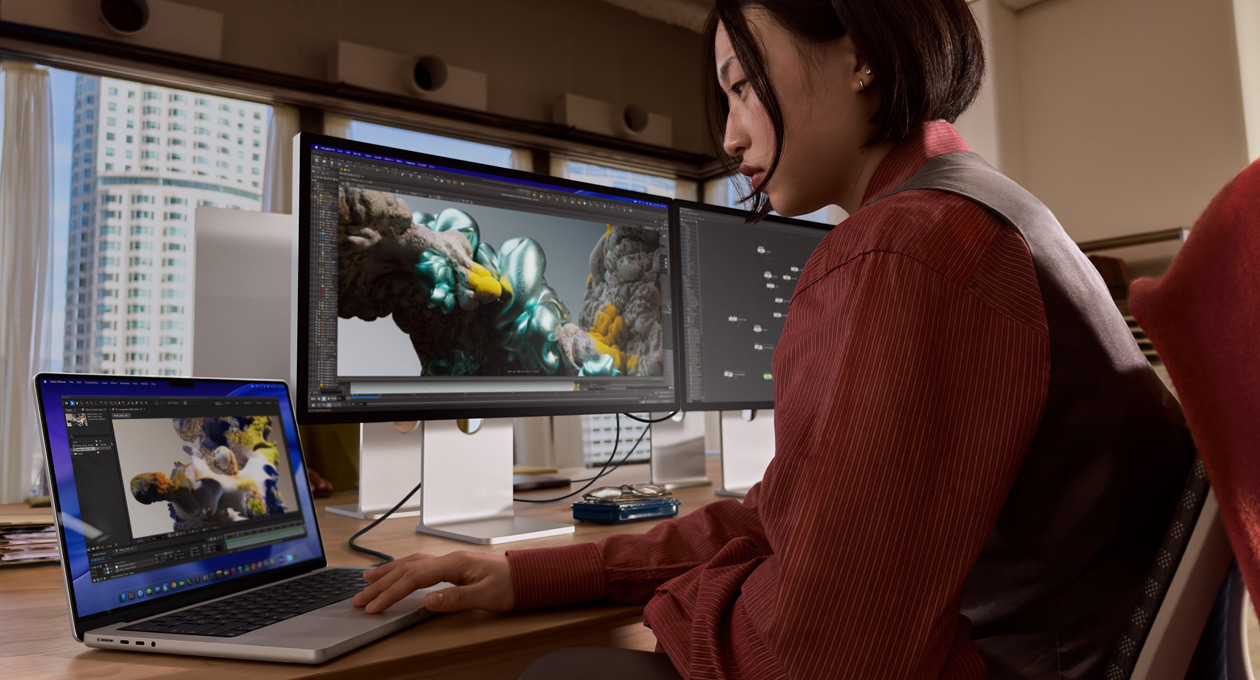 Henkilö työskentelee toimistoympäristössä MacBook-kannettavalla, johon on liitetty Studio Display XDR ‑näyttö Thunderbolt 5 ‑portin kautta