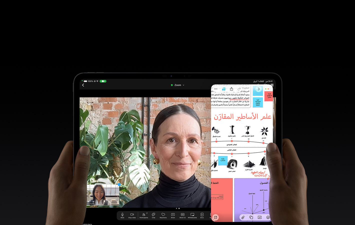 جهاز iPad&nbsp;Pro، الجزء الأمامي الخارجي، لون أسود فلكي، يدان يسرى ويمنى تحملان الجهاز في الوضع الأفقي، زوايا مدورة، إطار شاشة أسود، واجهة تعرض محادثة فيس&nbsp;تايم تُترجم مباشرةً، وتطبيق تعليمي يُظهر عرضاً تقديمياً عن 