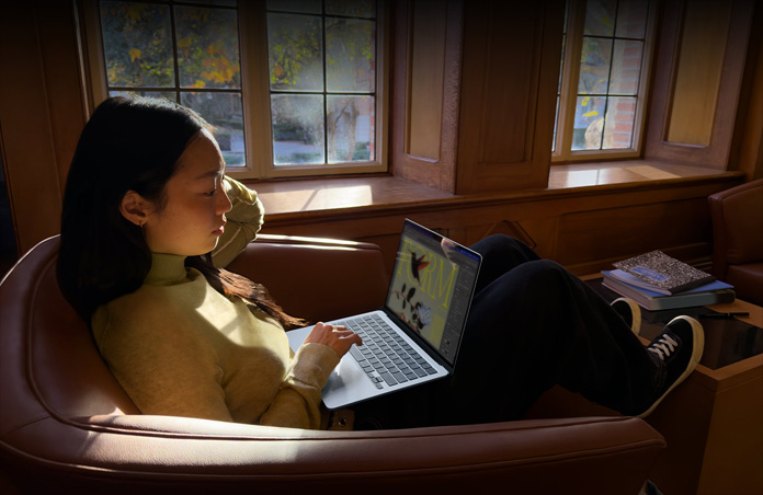 Koltukta oturan ve MacBook Air kullanan bir kişi