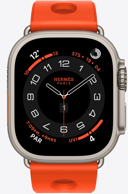 Apple Watch Hermès Ultra 3, Circulaire analogue watch face, (hour, minute and second hands, complications: Weather, activity rings, Paris time and UV Index), titanium case, natural colour, right side exterior, Digital Crown, raised side button, paired with Scub’H Diving strap, orange néon colour (bright orange), moulded rubber material, circular cutouts centred