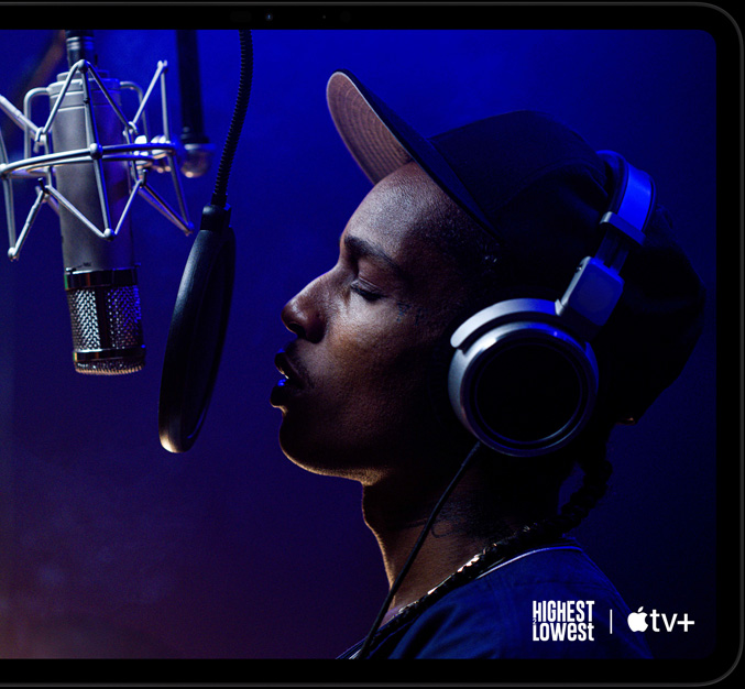 iPad Pro, landscape orientation, front exterior, space black color, rounded corners, black display bezel, display showing AppleTV+ playing a scene from  the Apple TV+ original film Highest 2 Lowest with ASAP Rocky as Yung Felon rapping into a microphone
