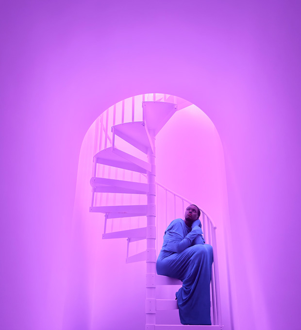 Close-up of a woman sitting on a spiral staircase demonstrating the pro camera system's low-light photographic capabilities